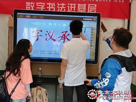 5数字书法展示台前，观众现场体验数字书法（图片来自网络）